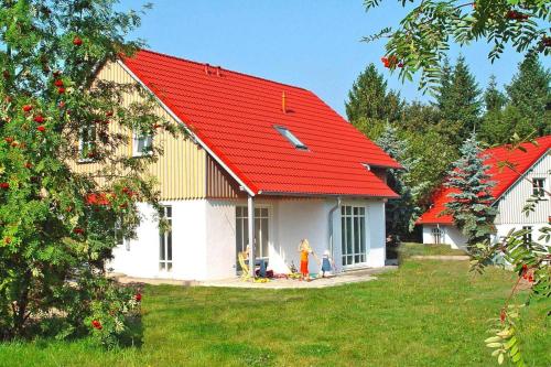 Eine Frau steht vor einem Haus mit rotem Dach. in der Unterkunft Holiday home in Wernigerode with a shared pool in Wernigerode