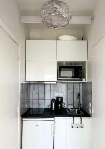une cuisine avec des armoires blanches et un micro-ondes dans l'établissement Résidence Eugenie - T2 rénové 4 pers. en 1ère ligne, accès direct plage MAE-9664, à Arcachon