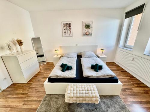 a white bedroom with two beds and two windows at FeWo Palmtrees 2 - Große und moderne 2 Zimmerwohnung mit französischem Balkon in Gladbeck-Mitte nähe Movie Park und Veltins Arena in Gladbeck