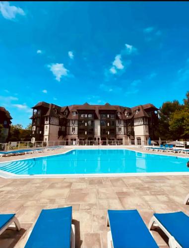 - une piscine avec des chaises bleues en face d'un bâtiment dans l'établissement Appartement T2 avec piscine, à Deauville