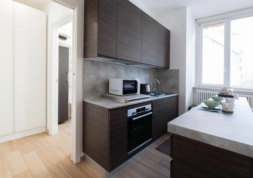 eine Küche mit Holzschränken und einer Mikrowelle in der Unterkunft AC Central Loft in Mailand