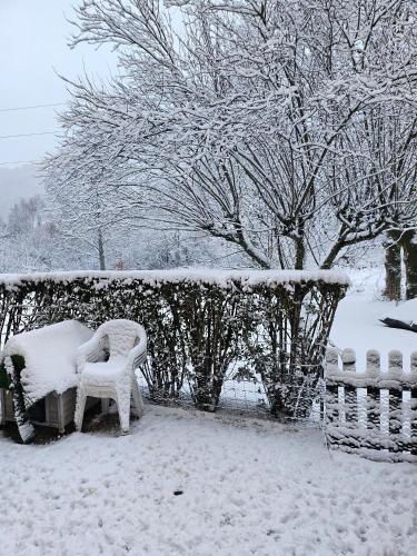 une cour enneigée avec deux chaises et une clôture dans l'établissement Kiki, à La Bourboule