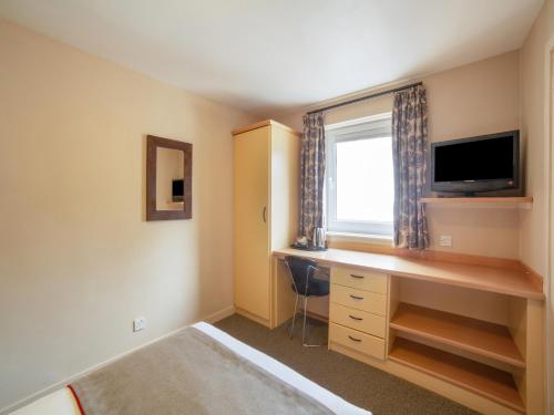 a bedroom with a desk and a tv and a window at Brentwood Aberdeen City Centre near Union Street in Aberdeen