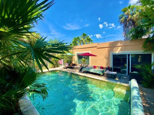 a swimming pool in front of a house with palm trees at Luxury house in Agde