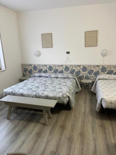 a bedroom with two beds and a bench in it at Affittacamere Cà della Roggia in Rovereto