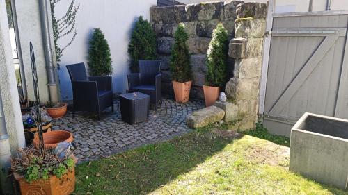 a patio with chairs and potted plants next to a building at Appartements an der Kaiserpfalz - Kaiserpfalz in Forchheim