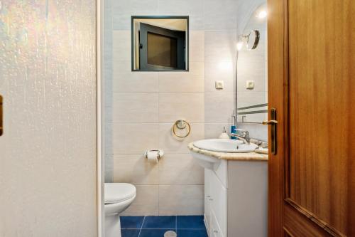 Un baño con inodoro, lavabo y espejo. en Casa Rocha, en Fajã da Ovelha