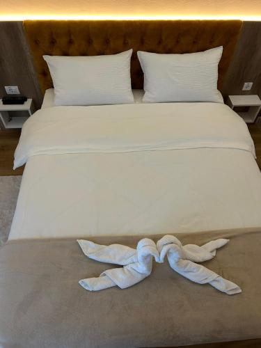 a white bed with two towels laying on it at Apartmani BOŽIČKOVIĆ in Palić