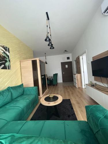 a living room with a green couch and a table at Apartmani BOŽIČKOVIĆ in Palić