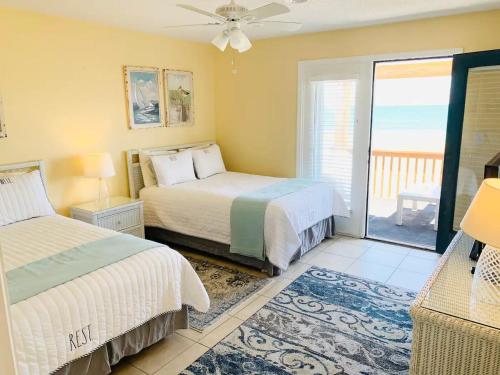 a bedroom with two beds and a balcony with the ocean at Sea Breeze, Beautiful Ocean Front Townhome in Kure Beach