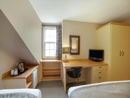 a bedroom with a desk with a television and a bed at Brentwood Aberdeen City Centre near Union Street in Aberdeen