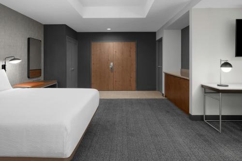 a bedroom with a white bed and a wooden door at Courtyard San Jose Airport in San Jose