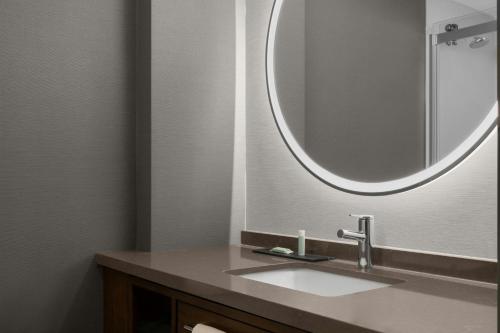 a bathroom with a sink and a round mirror at Courtyard San Jose Airport in San Jose