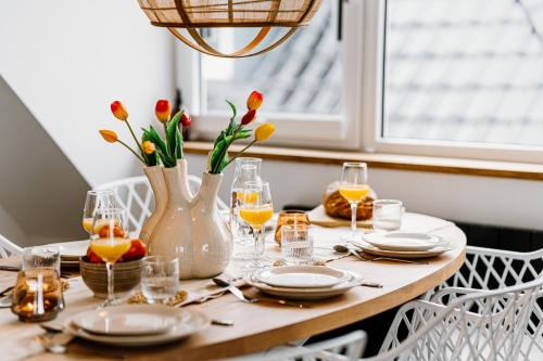 a table with plates and glasses and a vase with flowers at Lake House 10 - 4 Person Lake view Apartment! in Offingawier