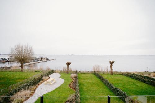 a dog sitting on a path next to the water at Lake House 10 - 4 Person Lake view Apartment! in Offingawier