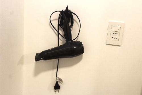 a black umbrella hanging on a wall next to an outlet at Habitación con baño privado independiente in Santiago
