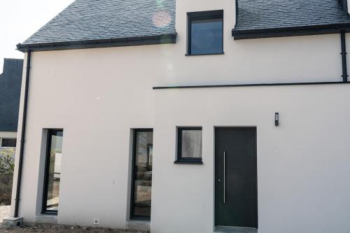 a white house with a black door and windows at Maison contemporaine Plescop in Plescop