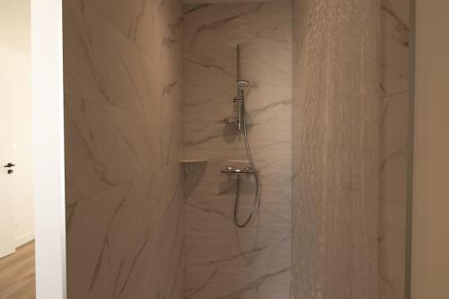 a bathroom with a shower with a stone wall at Maison contemporaine Plescop in Plescop
