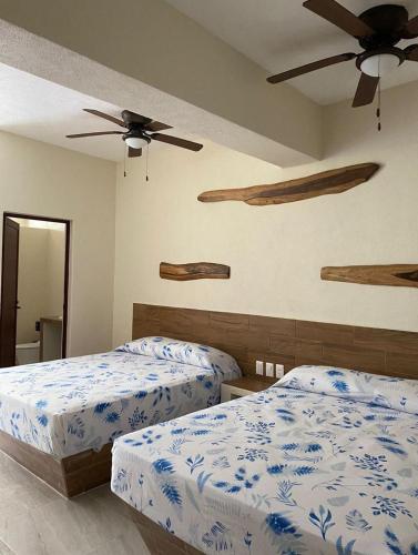 a bedroom with two beds and a ceiling fan at Bungalows Las Hamacas in San Patricio Melaque