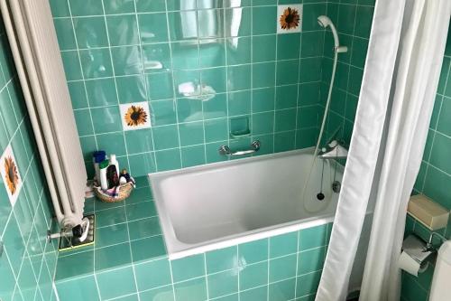 a green tiled bathroom with a tub and a shower at Casa del Noce - in the heart of Swiss Alps in Faido