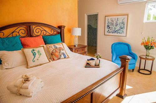 a bedroom with a large bed and a blue chair at walk to malecón, private Pool and Garden in La Paz