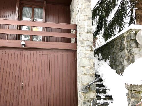 a red garage door with a window and a stone wall at Casa del Noce - in the heart of Swiss Alps in Faido