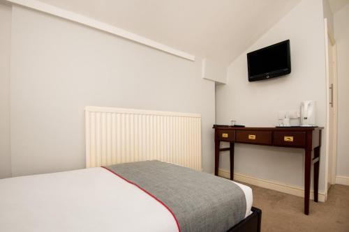 a bedroom with a bed and a desk with a television at The Regency, Clifton Bristol in Bristol