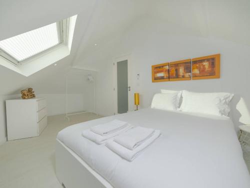a white bedroom with a large white bed with two towels at OPORTO GUEST - Maia House in Porto