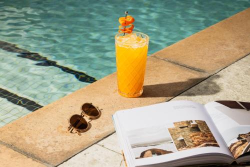 a book and a glass of orange juice next to a pool at Kimpton Hotel Palomar Phoenix Cityscape by IHG in Phoenix