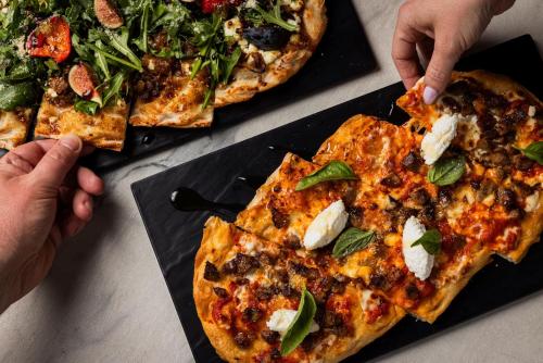 a person eating a slice of pizza on a table at Kimpton Hotel Palomar Phoenix Cityscape by IHG in Phoenix