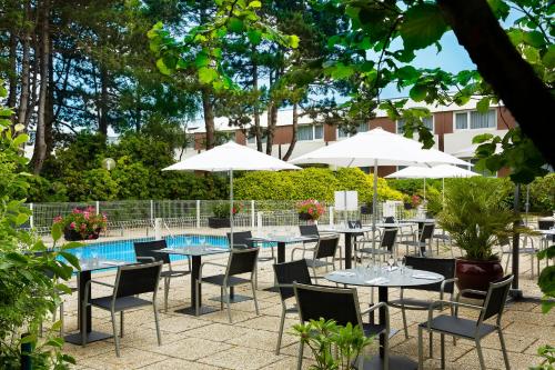 a patio with tables and chairs and umbrellas at Escale Oceania Brest in Gouesnou
