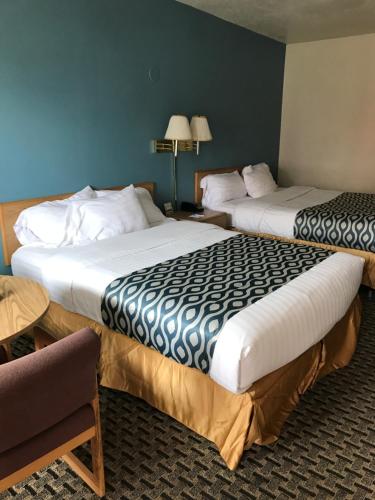 two beds in a hotel room with a chair at Vermilion Inn in Kanab