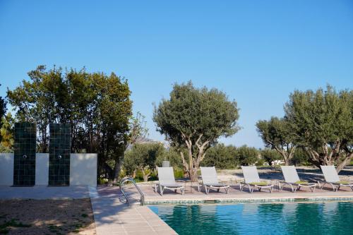 a row of lounge chairs next to a swimming pool at Hotel Finca Olivar in Benissa