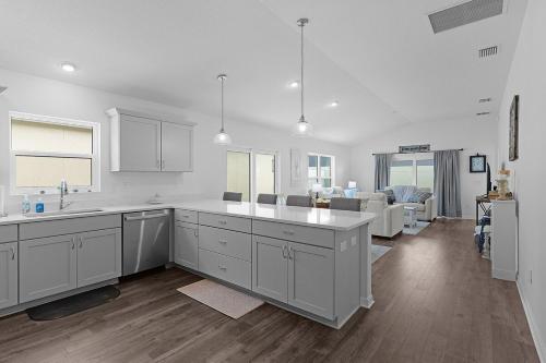 a kitchen with white cabinets and a living room at Cozy Family Stay- Queen-Double-Twins Bed- Full Kitchen-Netflix-Golf Cart-WiFi in Okahumpka