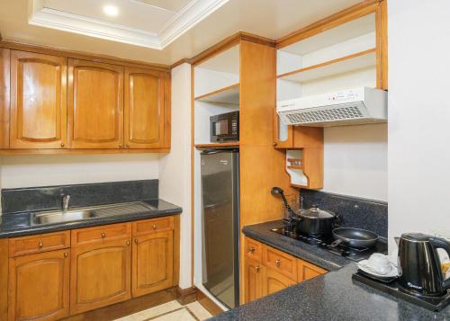 a kitchen with wooden cabinets and a sink at Richmonde Hotel Ortigas, Manila in Manila
