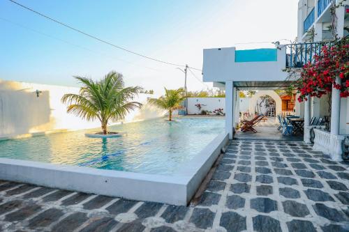 a swimming pool with palm trees next to a building at Pousada La Grécia in Camocim