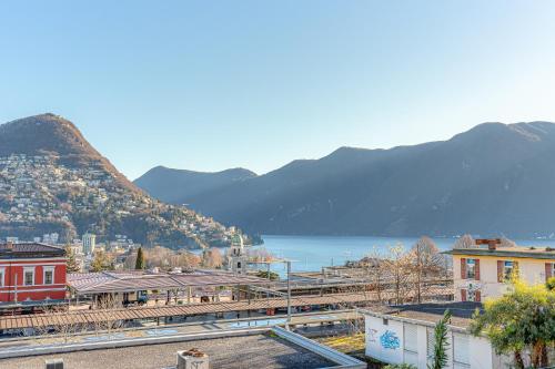 a town with a view of the water and mountains at IMPERIAL of LUGANO 3 with a lake view behind the station and 10 min from the lake of Lugano in Lugano