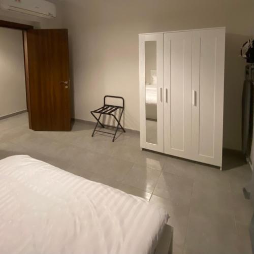 a bedroom with a bed and a chair next to a door at Lana's Studio in King Abdullah Economic City