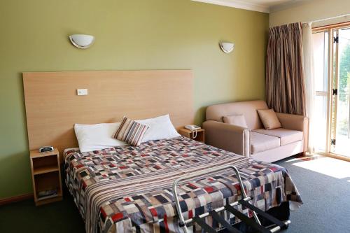 ein Schlafzimmer mit einem Bett, einem Stuhl und einem Fenster in der Unterkunft Forbes Victoria Inn in Forbes
