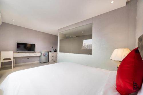 a white bedroom with a large bed and a tv at Collection O Sunshine Garden Hotel - Near SECC in Ho Chi Minh City
