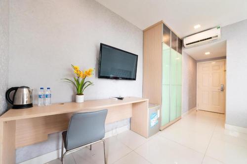 a room with a desk with a television on the wall at Collection O Sunshine Garden Hotel - Near SECC in Ho Chi Minh City