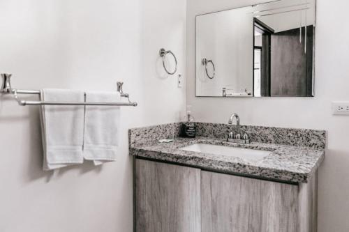 a bathroom with a sink and a mirror and towels at Casa Luna in Punta Leona