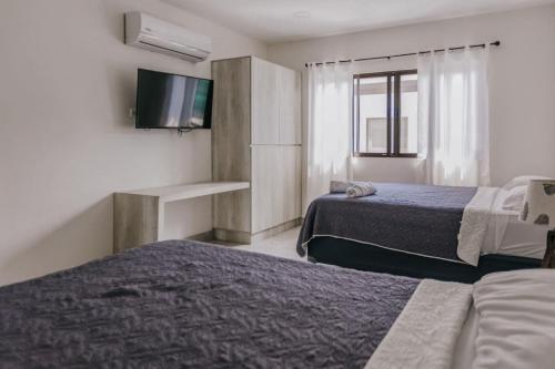 a hotel room with two beds and a flat screen tv at Casa Luna in Punta Leona