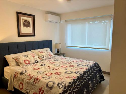 a bedroom with a bed with a flowered blanket and a window at Esmeralda apartment in Tarcoles