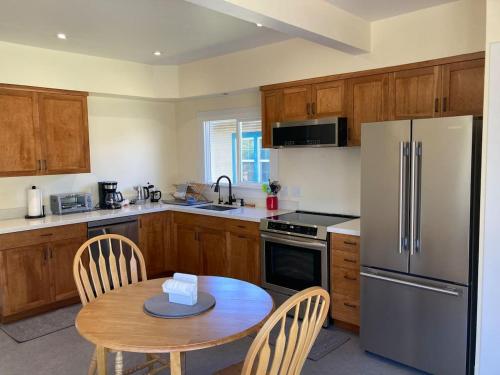 a kitchen with a table and a stainless steel refrigerator at Henderson Hideout Hot Tub and Pet Friendly. in Eureka