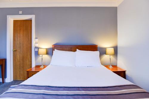 a bedroom with a large white bed with two lamps at Aston Court Derby City Centre by Belvilla in Derby