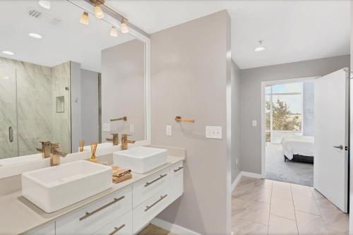 a white bathroom with two sinks and a mirror at Modern 3 bedroom condo in downtown w free parking in Orlando