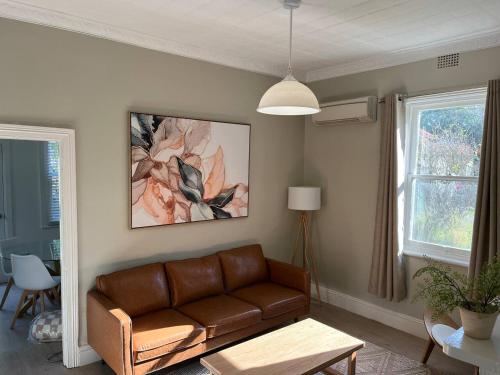 a living room with a brown couch and a window at Beautiful comfortable cottage in Orange