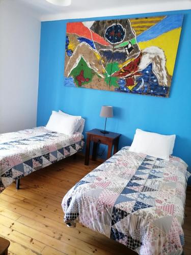 two beds in a room with a painting on the wall at Casa das 4 estações in Castelo Branco