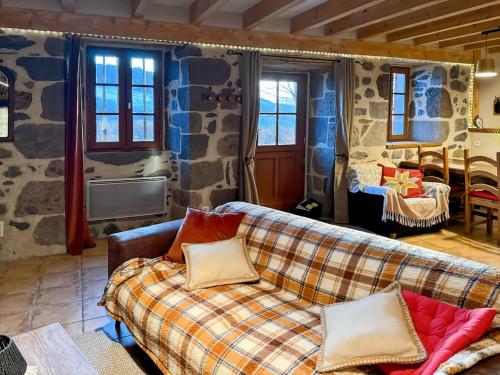 un salon avec un canapé et un mur en pierre dans l'établissement Le refuge de la vallée - 4 à 6 pers - proche de Salers, à Saint-Projet-de-Salers